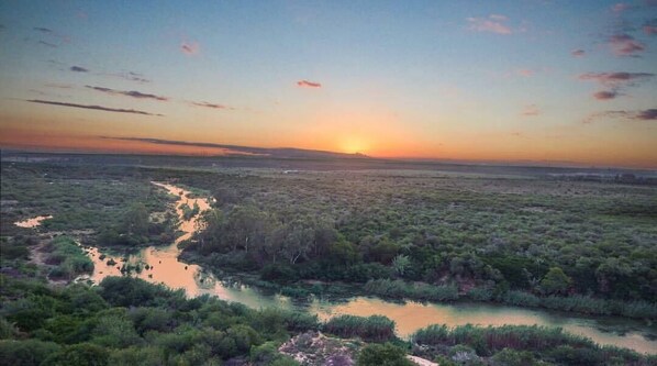 A landscape with a river and dense vegetation during sunset.