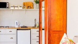 Una cocina con armarios blancos, un refrigerador blanco, un mueble de madera y un microondas en la encimera.