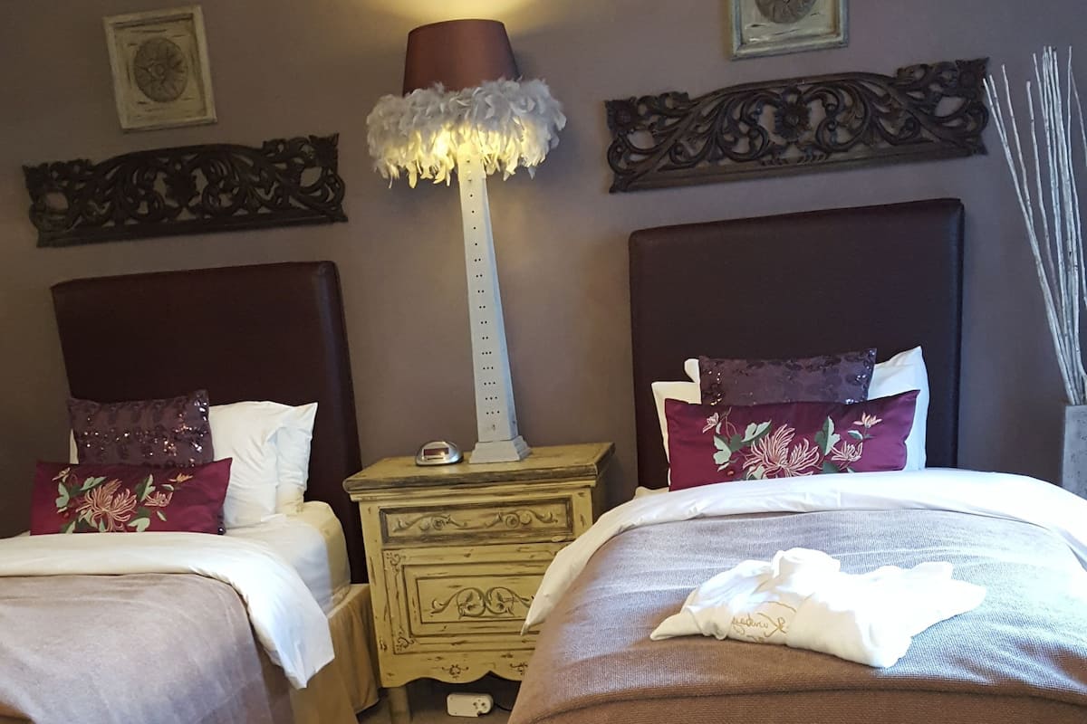 A hotel room with two beds, a nightstand, a lamp, and decorative wall art.