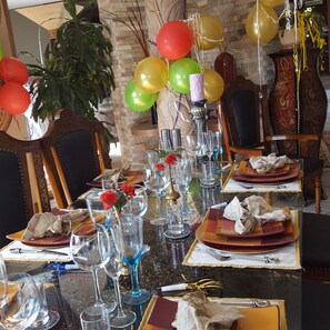 A dining table set with multiple wine glasses, plates, and cutlery, surrounded by chairs. - Kumbaya House (Cape Town)