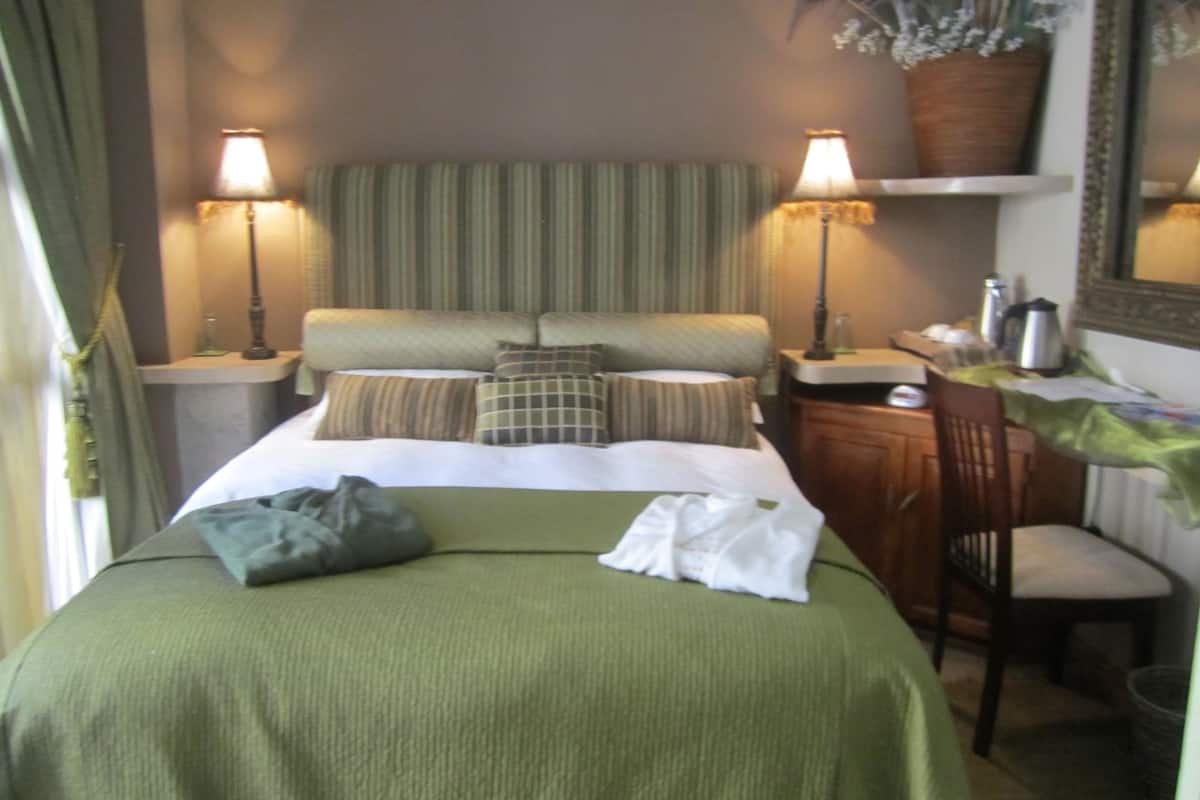 A hotel room with a bed, two bedside tables, a desk, a chair, and a mirror.