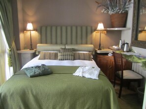 A hotel room with a bed, two bedside tables, a desk, a chair, and a mirror. - Kumbaya House (Cape Town)