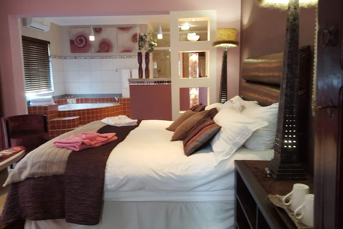 A hotel room with a bed, a bathroom with a bathtub, and a shower.