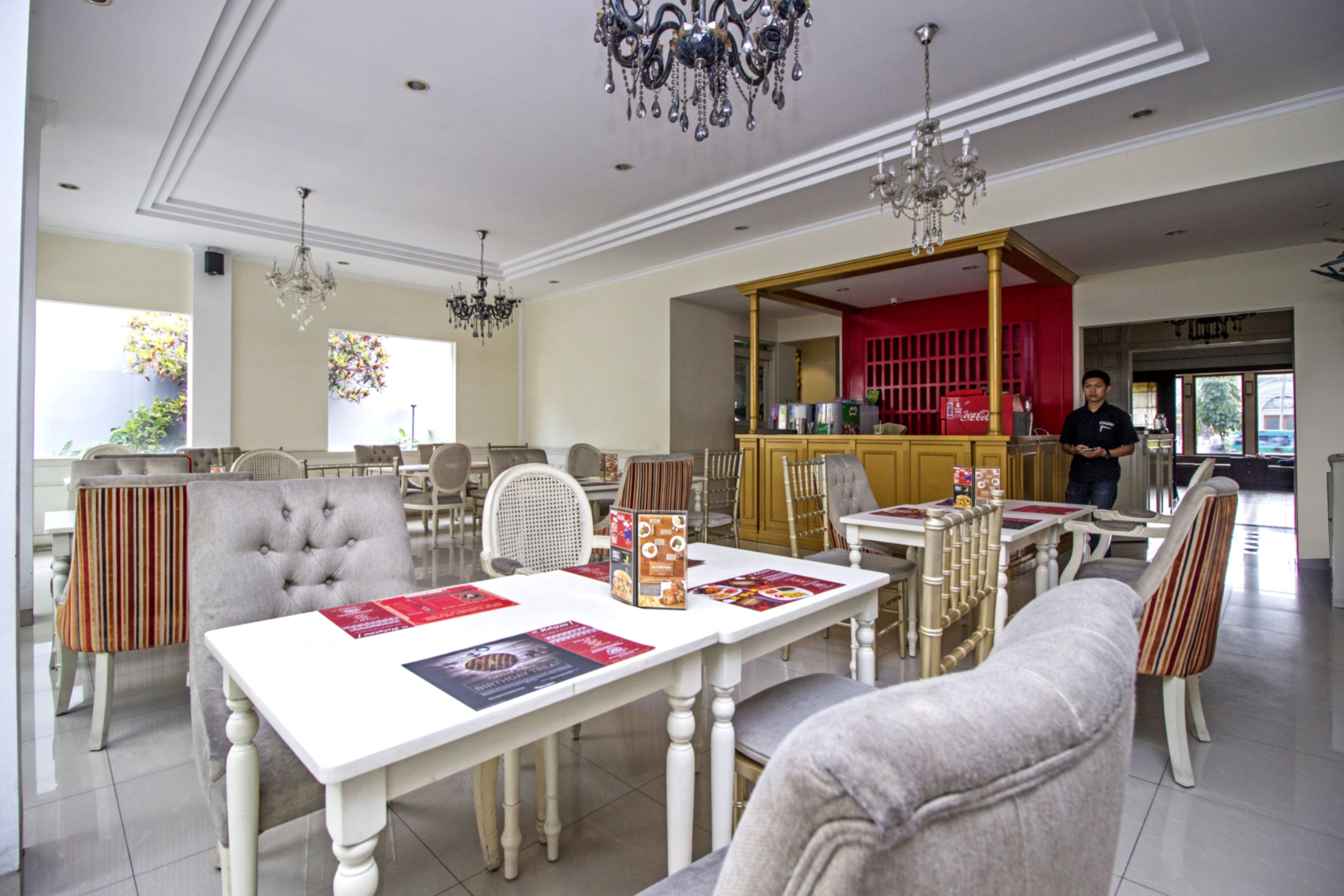 A spacious dining area with multiple tables and chairs, a bar area, and a kitchen in the background.