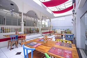 A spacious restaurant with high ceilings, wooden tables, and colorful chairs.