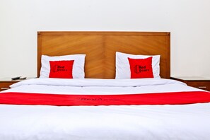 A bed with white bedding and two red pillows with black text.