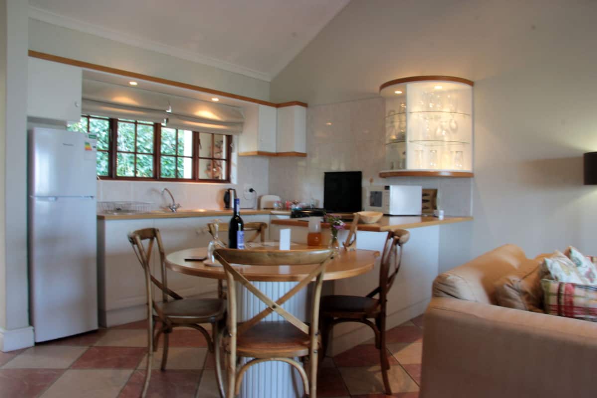 Una cocina compacta con zona de comedor, refrigerador, lavamanos y televisor integrado.