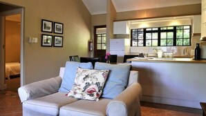 Ein Wohnzimmer mit einer Couch, einer Küchenzeile mit Fenster und einem Bett im Hintergrund.