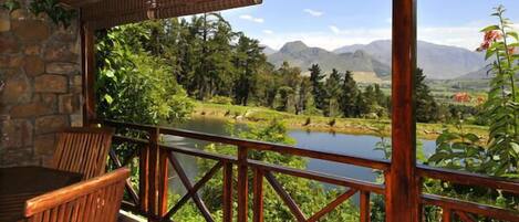 A wooden deck with a view of a lake and mountains.