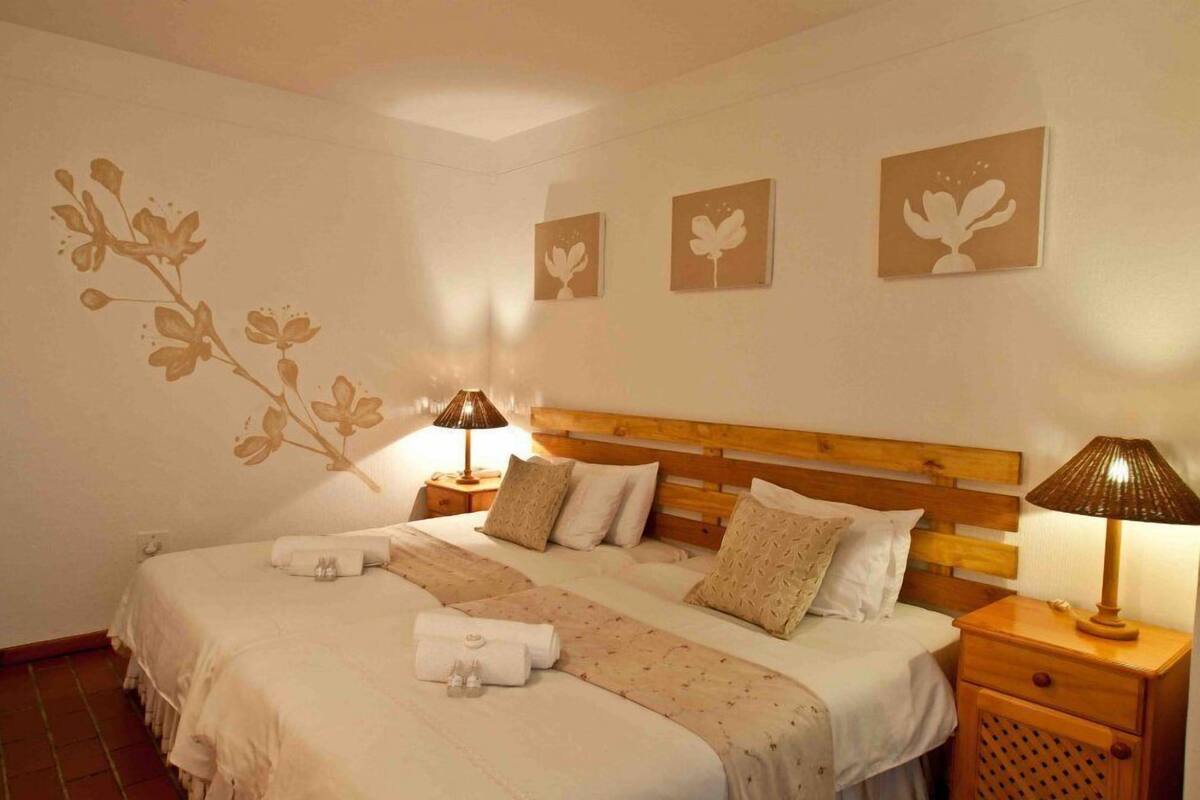 A hotel room with a large bed, two bedside tables, and wall art.