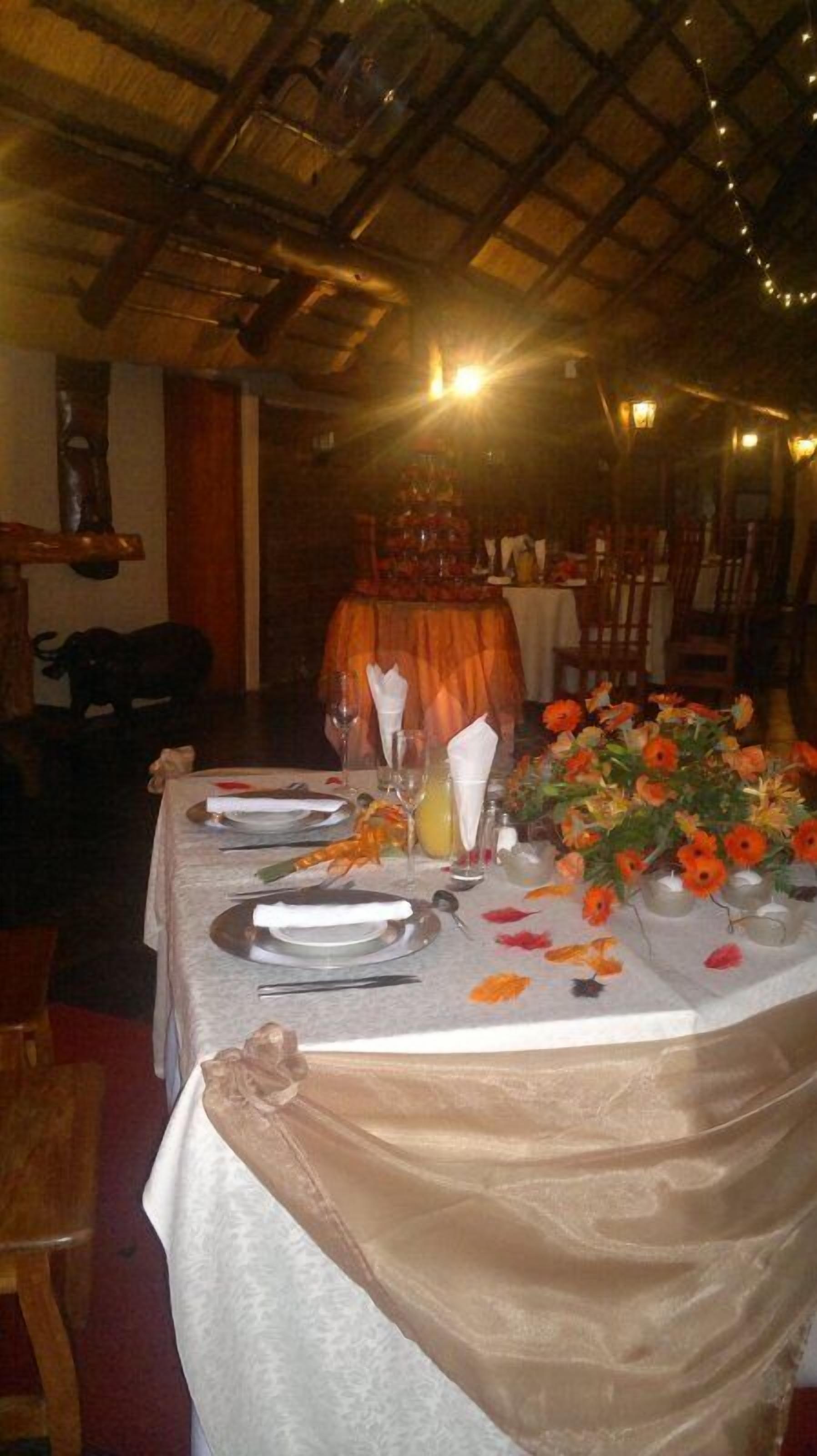 Taula de menjador preparada amb plats, gots i un arranjament floral taronja.