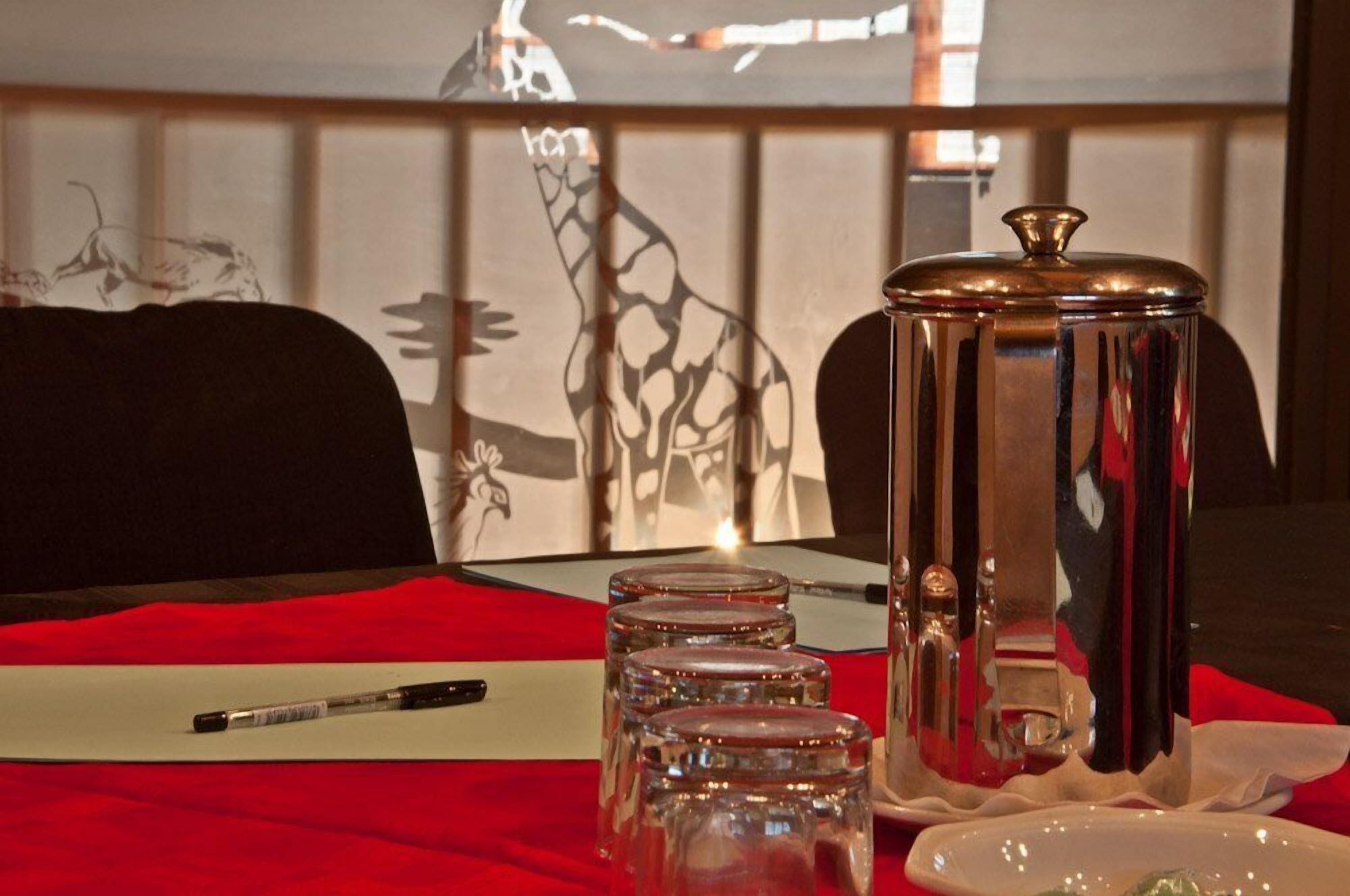 A table with a red tablecloth, a pen, three glass jars, and a metal container with a lid.