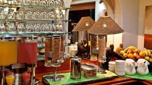 Buffet-alue, jossa on tarjolla monenlaista ruokaa, kahvipiste ja valikoima lasiesineitä hyllyillä.