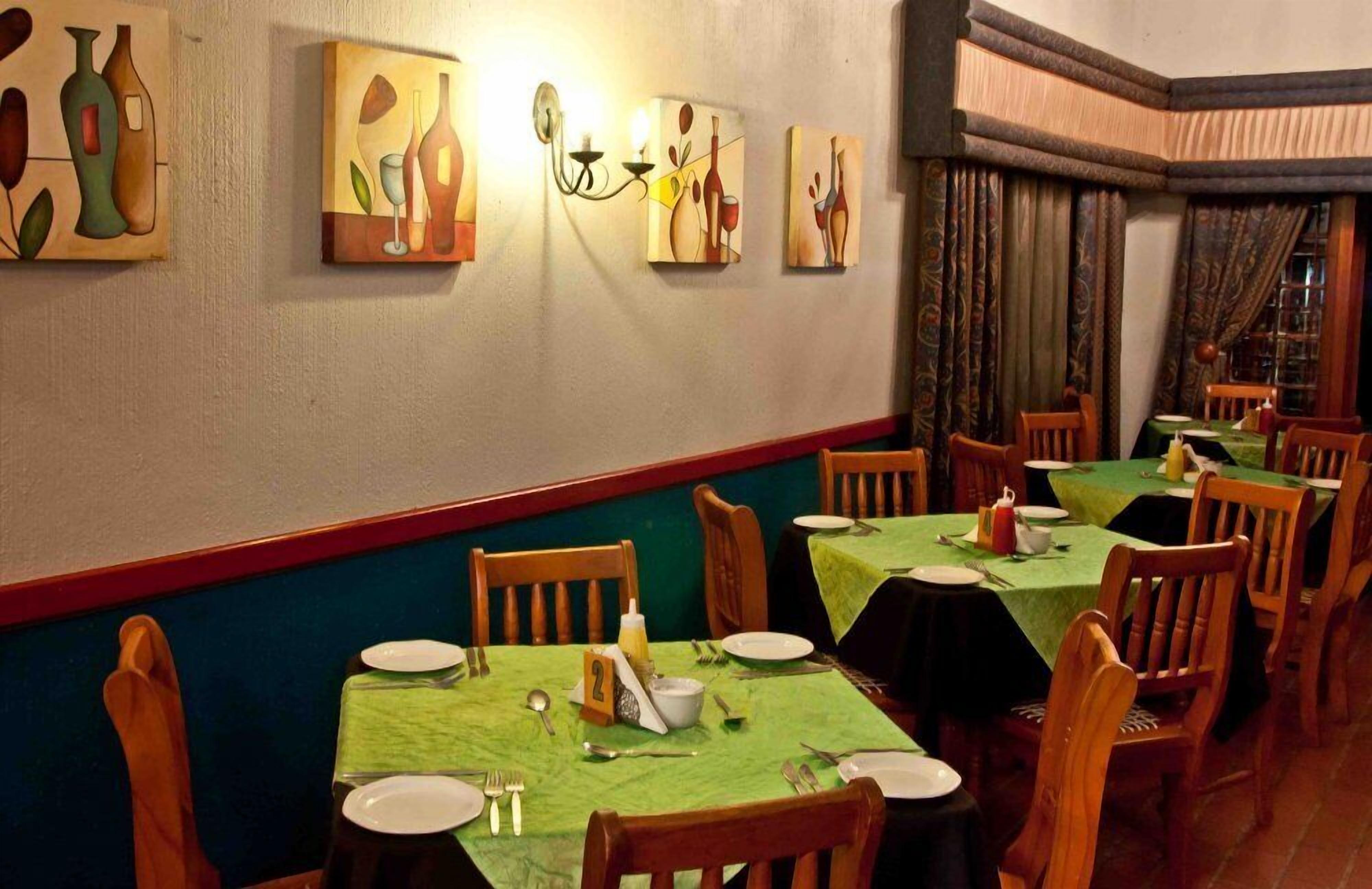 Un restaurante con mesas dispuestas para comer, sillas y decoración en las paredes.