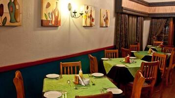 Un restaurante con mesas dispuestas para comer, sillas y decoración en las paredes.