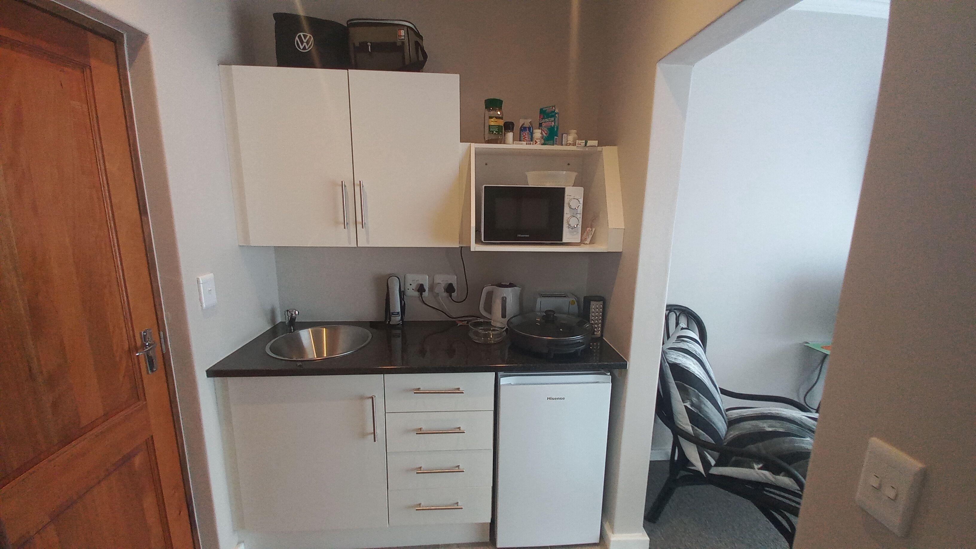 A compact kitchenette with a sink, microwave, and storage cabinets.