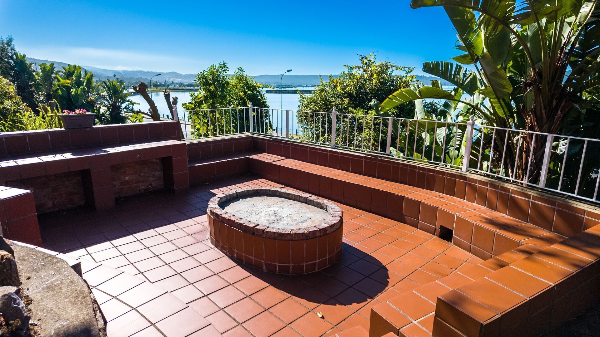 An outdoor patio with a fire pit, seating areas, and a view of a lake and mountains.