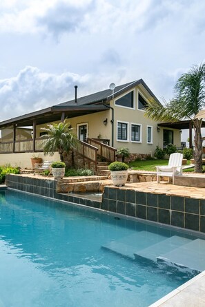 Una piscina al aire libre, sombrillas, sillones reclinables de piscina