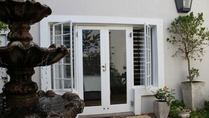A stone fountain in a courtyard with a white door and a potted plant nearby.