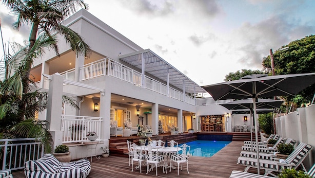 A two-story building with a pool, outdoor seating, and a bar area.