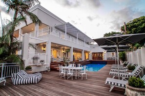 A two-story building with a pool, outdoor seating, and a bar area. - Sandals Guest House (Umhlanga)