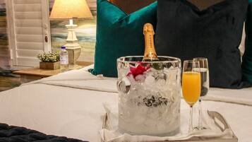 Una cama con una botella de champán, copas y hielo en un recipiente de vidrio.