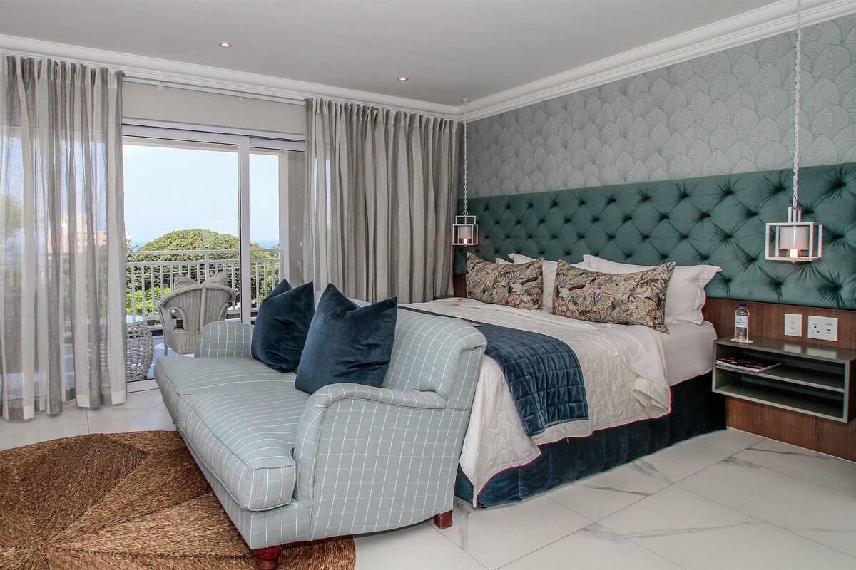 Ein Schlafzimmer mit einem großen Bett, einer Couch und Blick ins Freie.