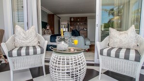 A living room with two wicker chairs, a round table, and a sofa.
