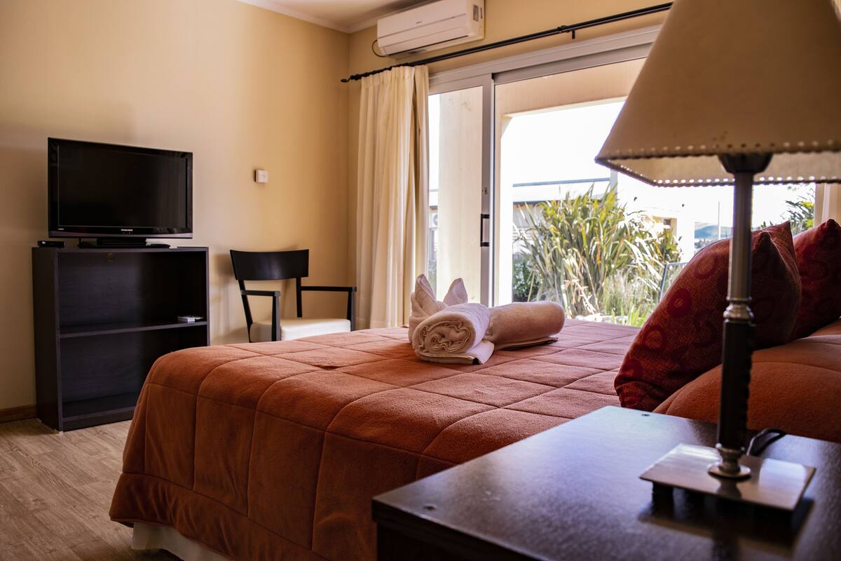 Een hotelkamer met een bed, een televisie, een bureau, een lamp en uitzicht op het landschap.
