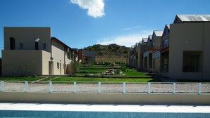A poolside view of a hotel with a clear blue pool, a well-maintained lawn, and a hilly landscape in the background. - Posada y Spa Las Golondrinas (Villa La Arcadia)
