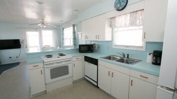 A compact kitchen with white cabinets, a microwave, a stove, a dishwasher, and a sink.