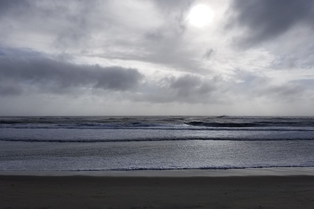 Uma praia com ondas e céu nublado.