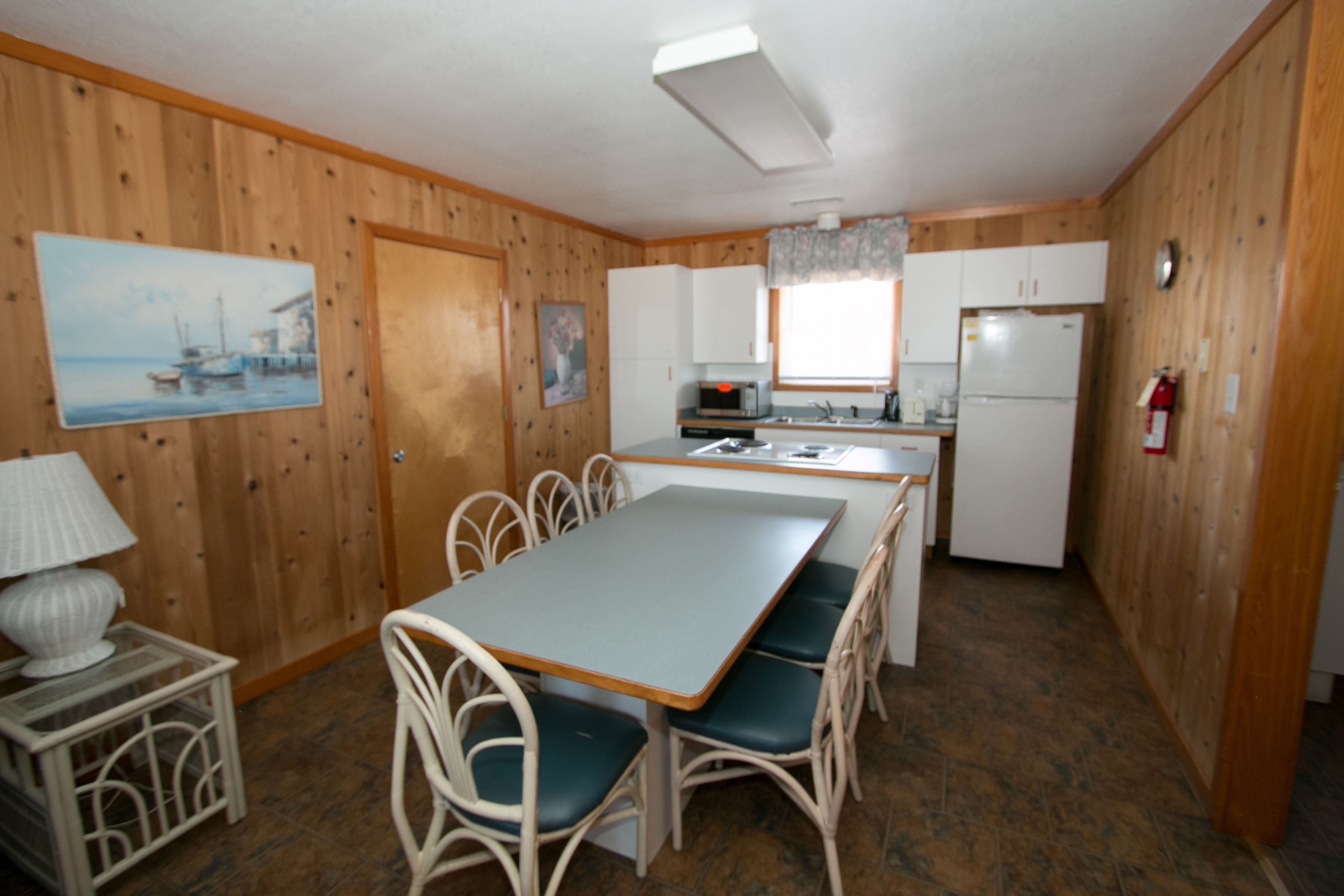 Une cuisine de taille réduite avec des murs en bois, une table à manger avec des chaises et un réfrigérateur.