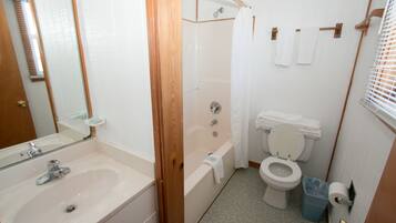 A bathroom with a sink, bathtub, toilet, and shower curtain.