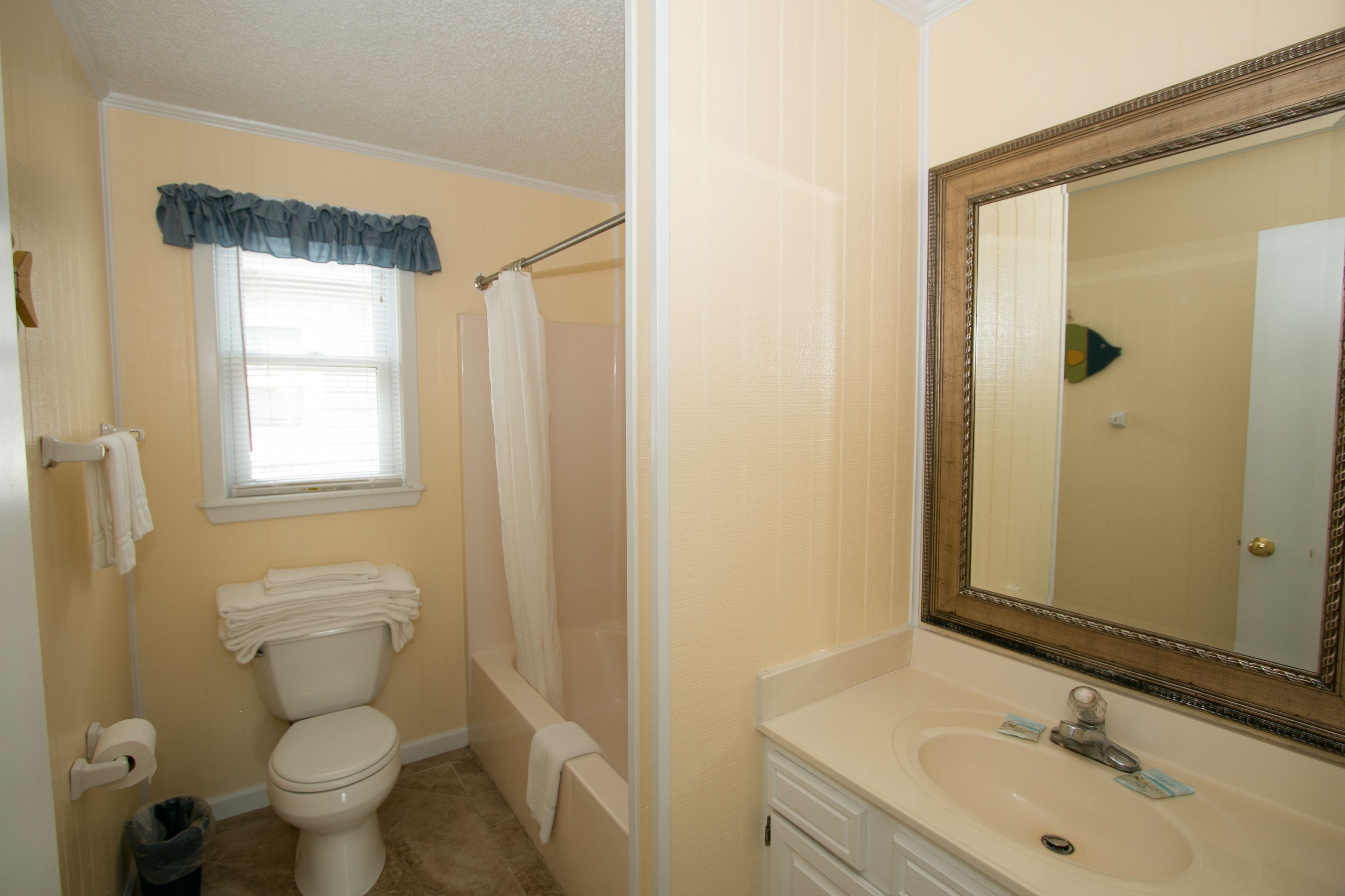 A bathroom with a toilet, a bathtub, a sink, and a mirror.