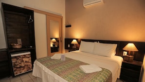 Ein Hotelzimmer mit einem Bett, Nachttischlampen, einem Spiegel, einem Holzschrank und einem kleinen Tisch mit einer Lampe.