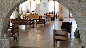 A spacious lobby with a stone archway, wooden furniture, and a tiled floor. - Eri Hotel (Paros)