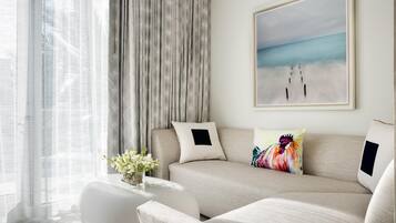 A modern living room with a sofa, a coffee table with a vase of flowers, and a painting of a beach scene.