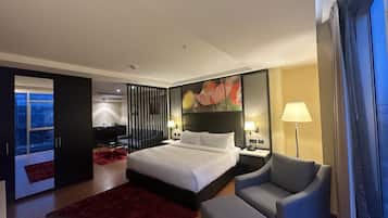 Habitació d'hotel amb un llit, una cadira, escriptori, làmpada i un quadre.