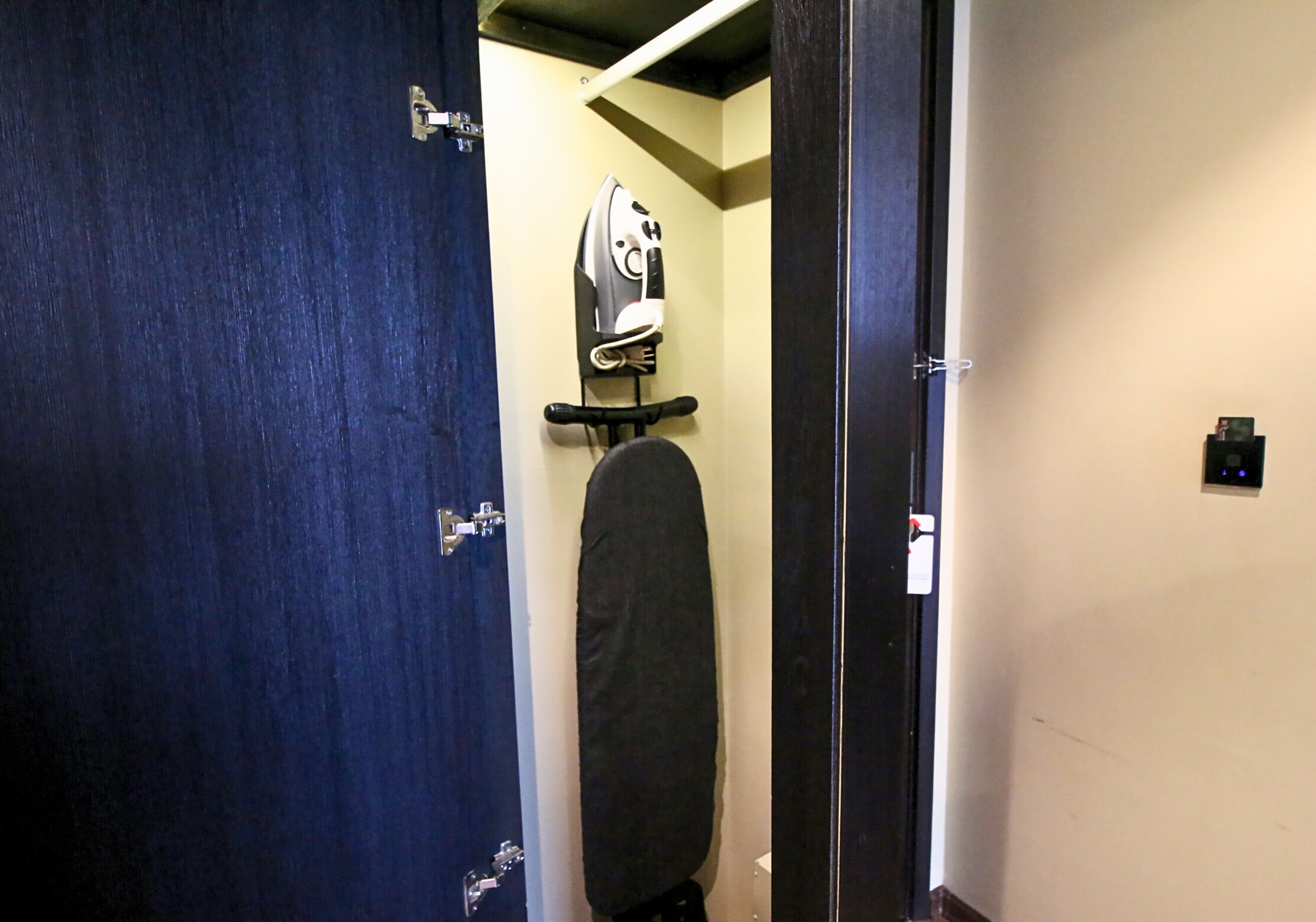 A room with a blue door, a blackboard, and a wall-mounted iron.