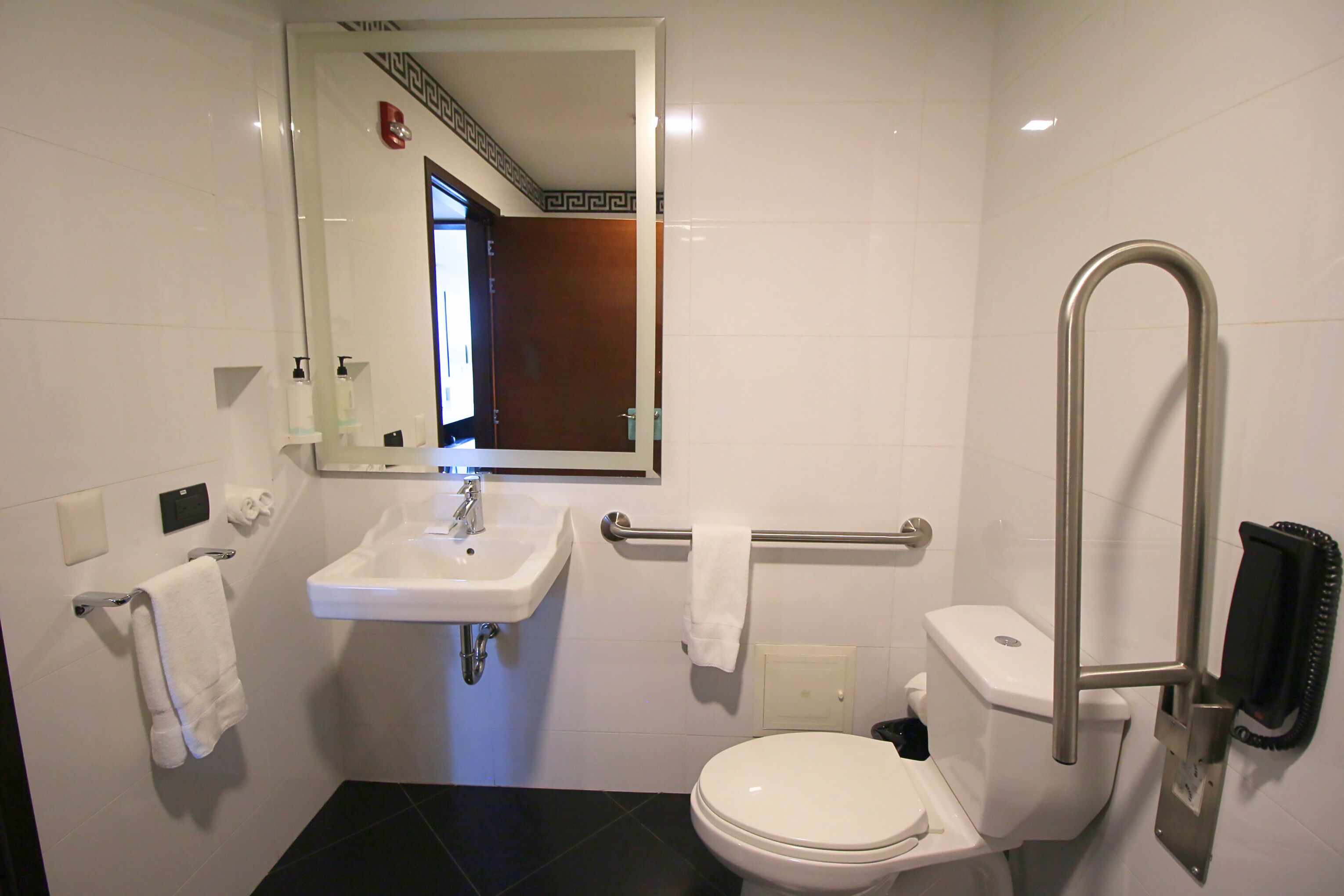 Un baño moderno con un lavabo blanco, inodoro y un espejo sobre el lavabo.