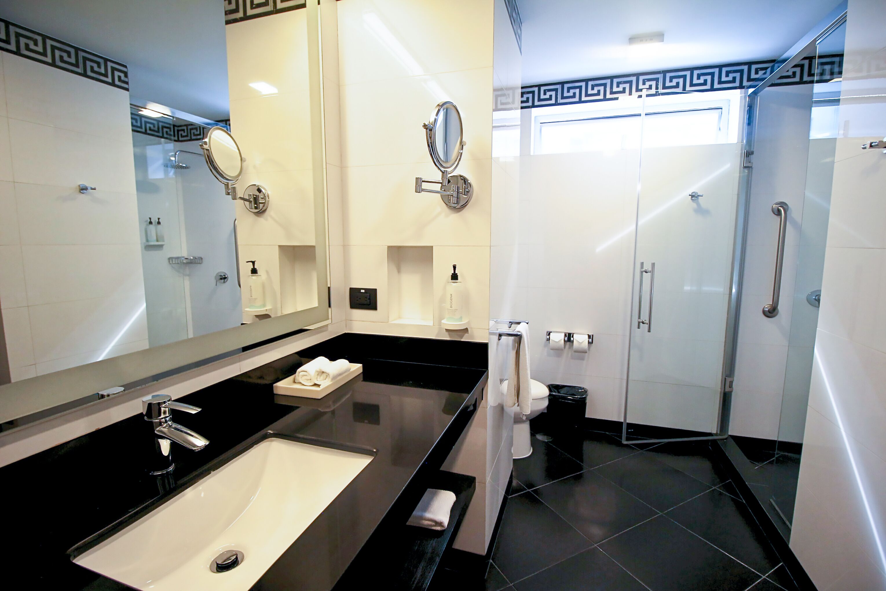 A modern bathroom with a black countertop sink, a large mirror, and a glass-enclosed shower area.