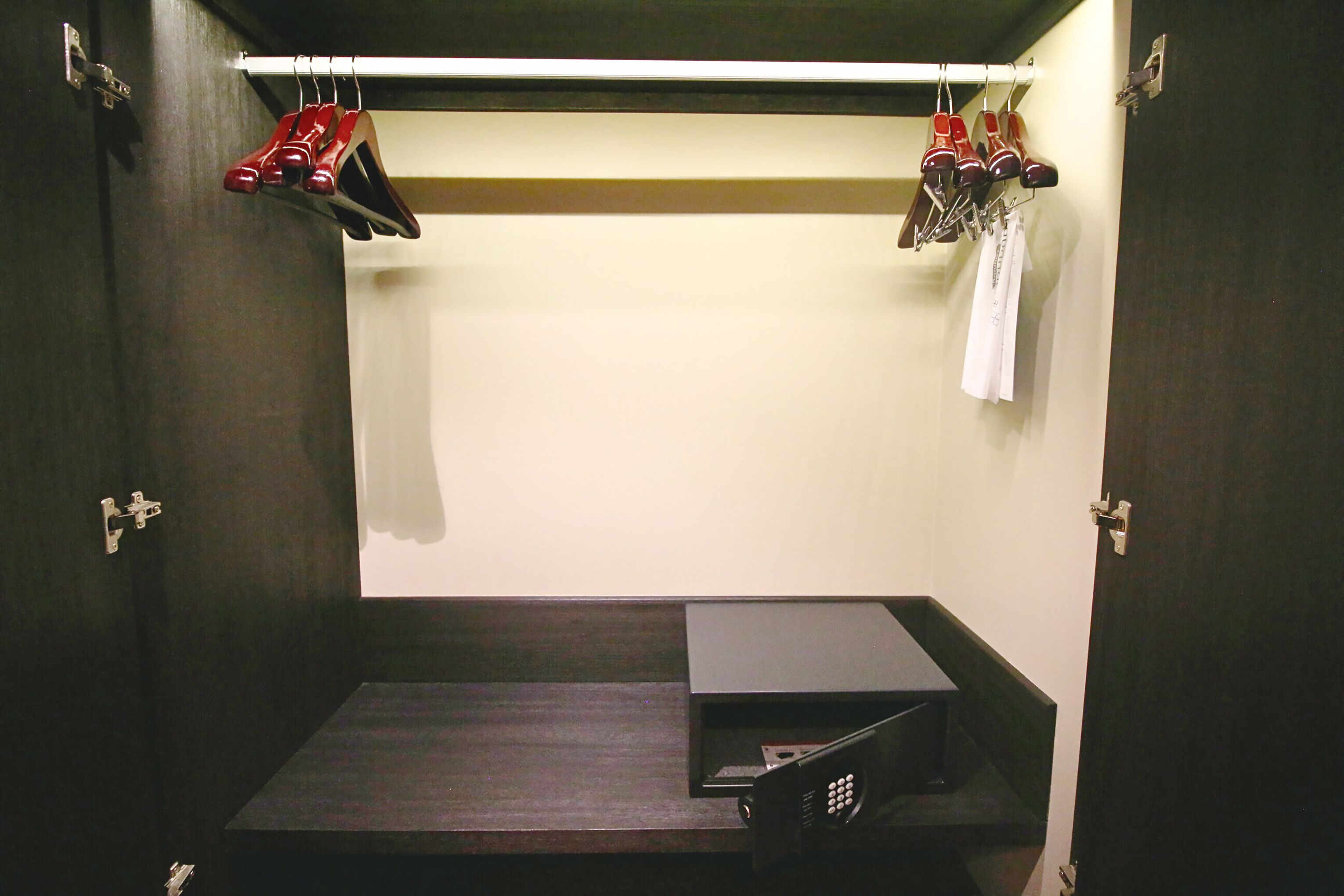 Une pièce de taille modeste, avec une armoire en bois foncé, un petit bureau et un porte-chaussures contenant des chaussures rouges.