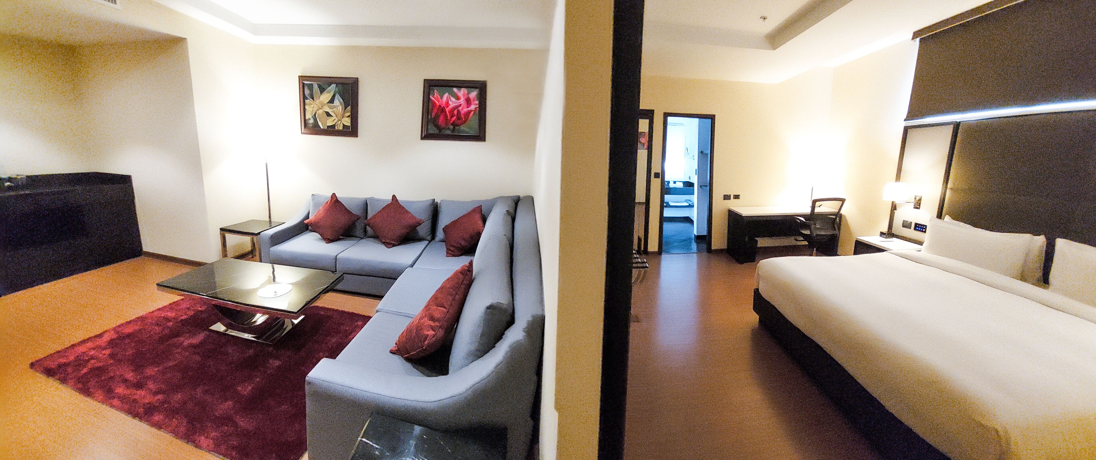 A hotel room with a sofa, a coffee table, a bed, and a desk with a chair.