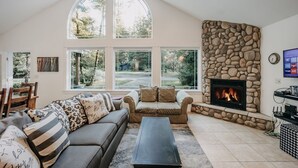 A spacious living room with a stone fireplace, large windows, and a cozy seating area. - 01sl - Hot Tub - Pet Friendly - Bbq - Sleeps 8 3 Bedroom Home by RedAwning (Deming)