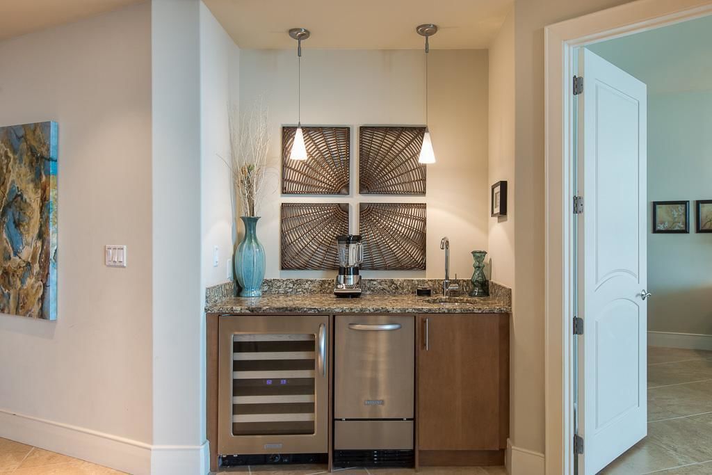 A modern kitchen with stainless steel appliances, a granite countertop, and pendant lighting.