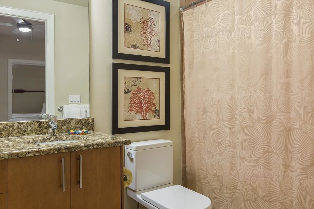A bathroom with a toilet, sink, and framed artwork on the wall.