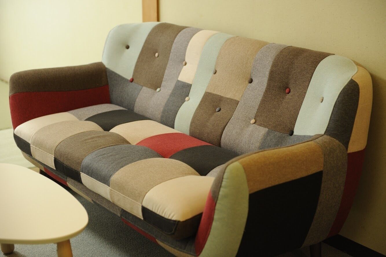 A sofa with a multicolored striped pattern and tufted backrest.
