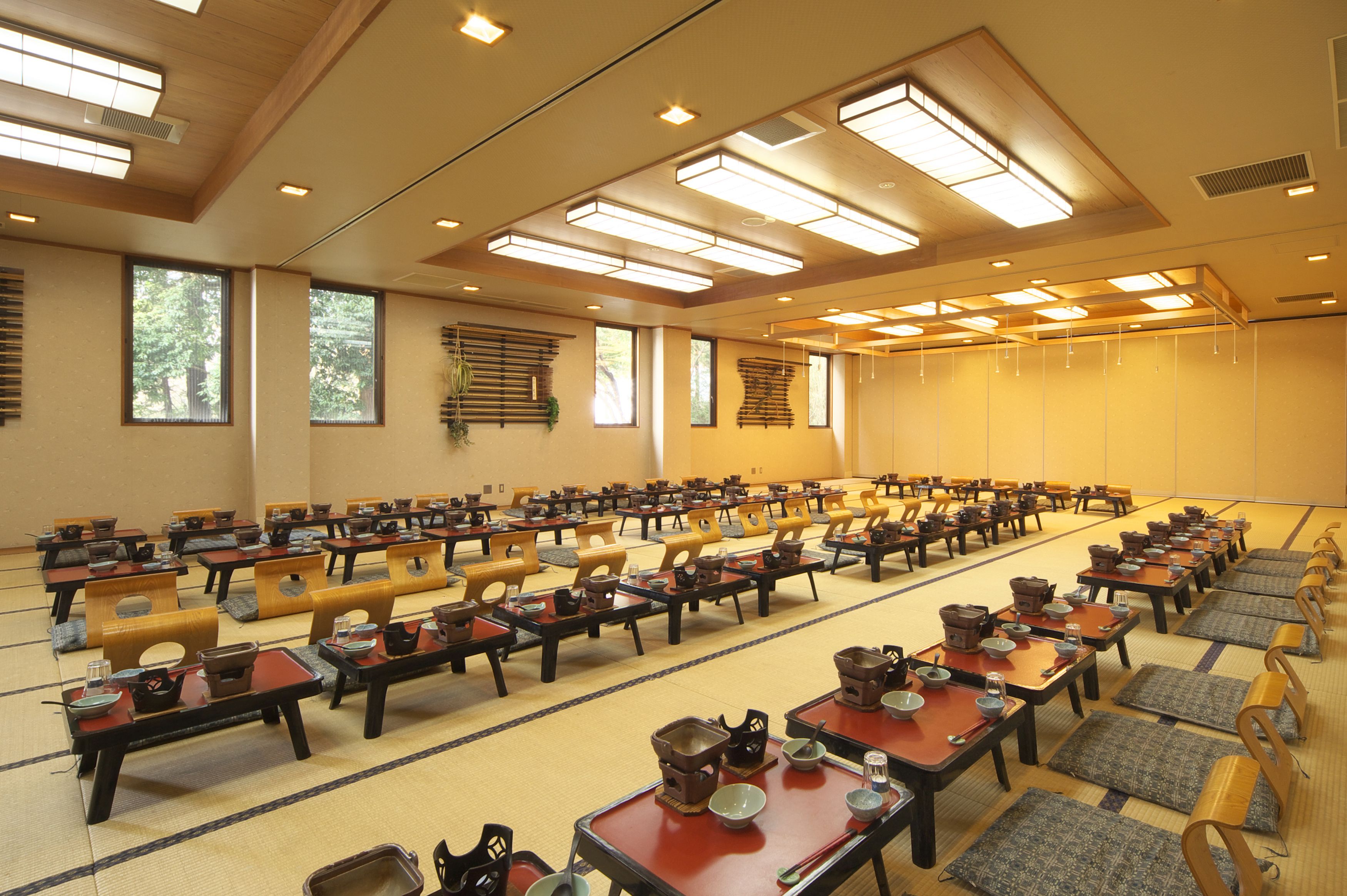 Un salón de conferencias con filas de mesas dispuestas para una reunión, equipado con juegos de té tradicionales japoneses.