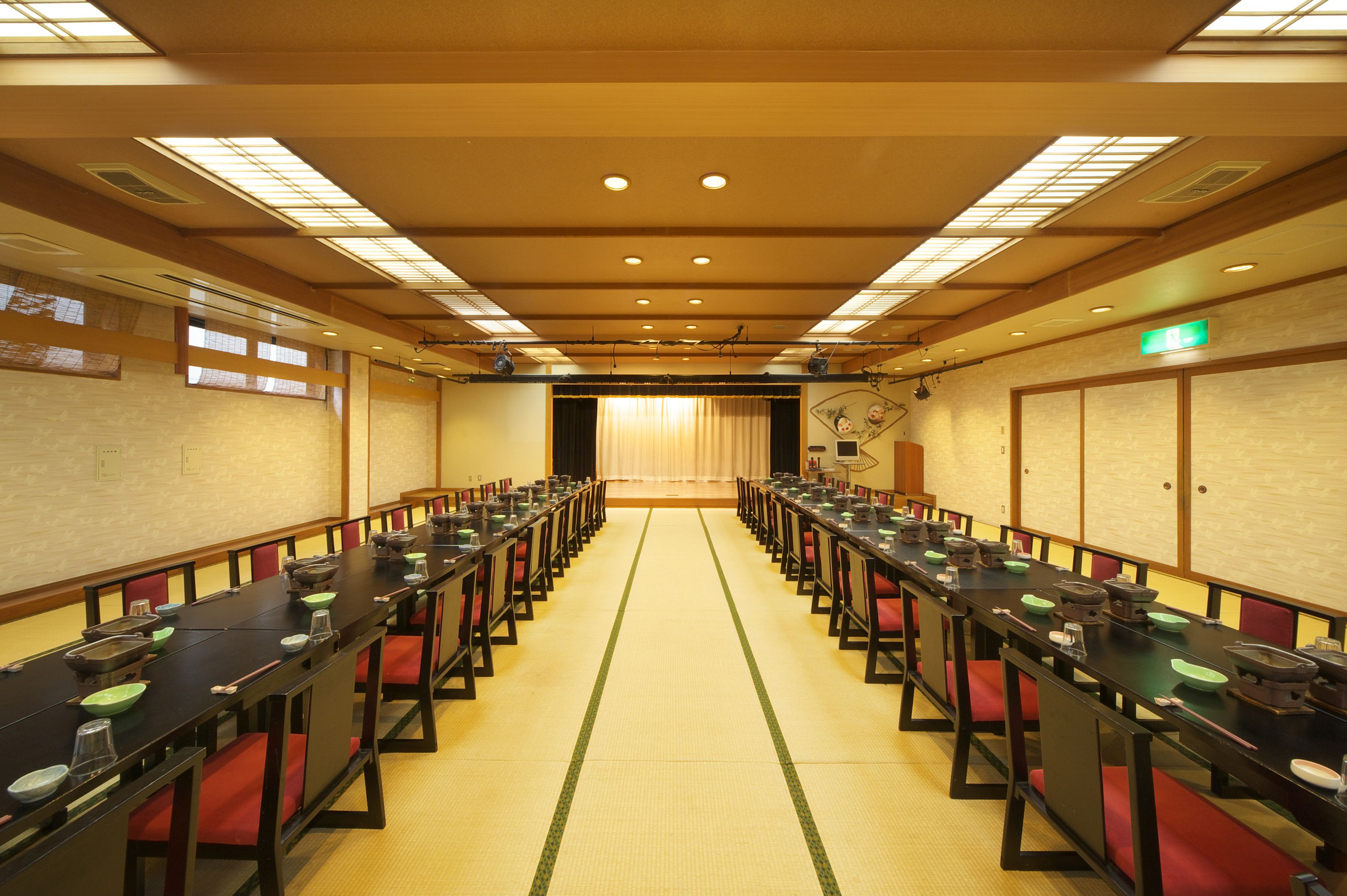 Ein Konferenzraum mit langen Tischen, roten gepolsterten Stühlen und einem traditionellen japanischen Tatami-Boden.